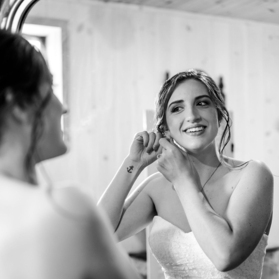 Bride fixes her earring in the mirror (photo in black and white).